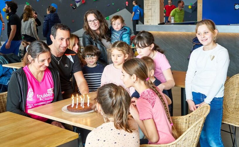 Des enfants et parents en train de souffler les bougies d'un gâteau maison